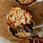 Single bowl of French Onion Cheesesteak Soup with bubbling cheese and toasted bread on top