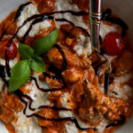 Close up of creamy burrata gnocchi with sausage and melted burrata.