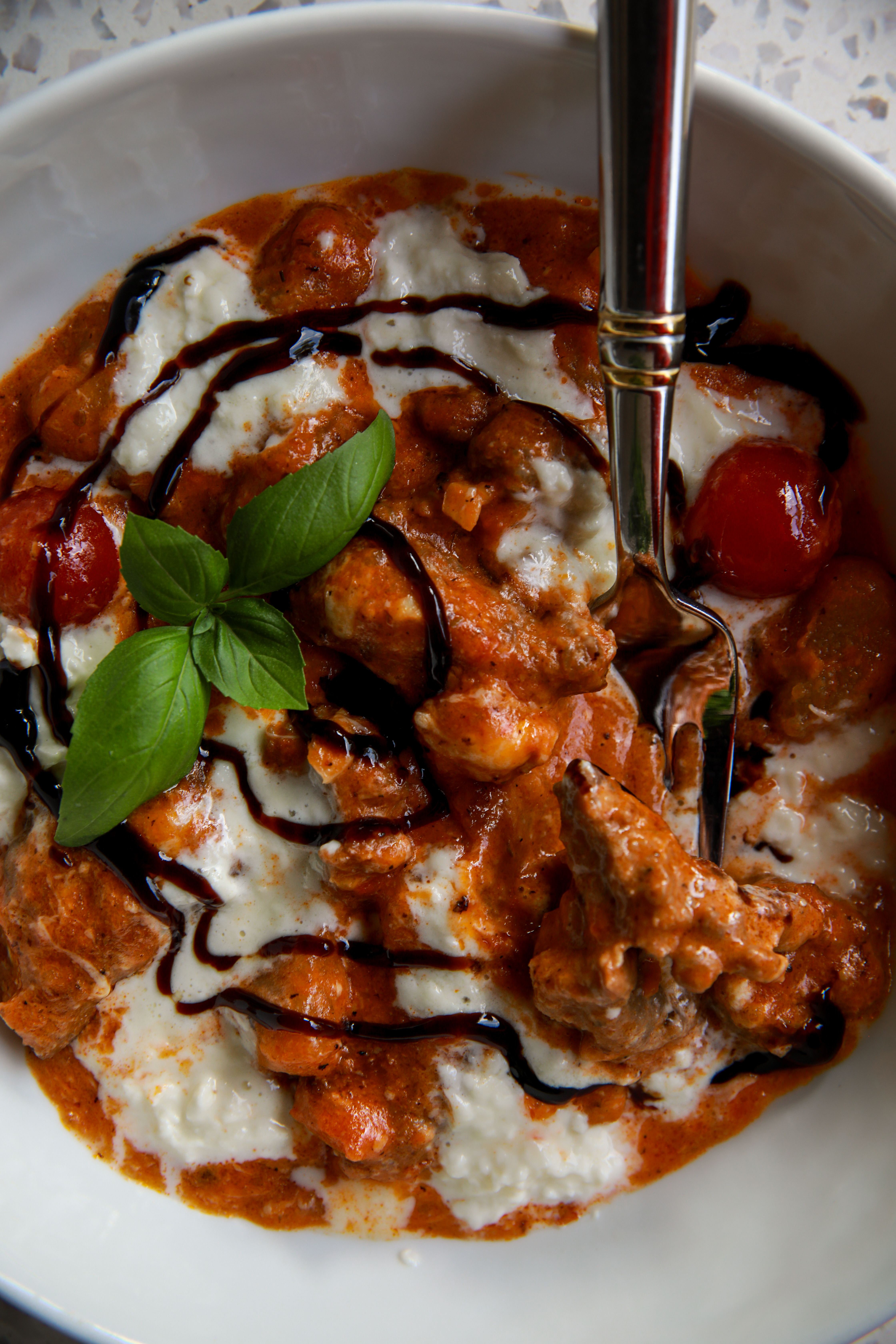 Close up of creamy burrata gnocchi with sausage and melted burrata.