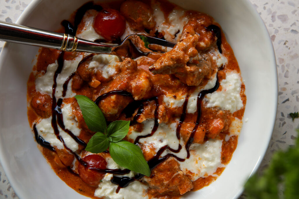 One pan creamy burrata gnocchi topped with burrata, basil, and balsamic glaze.