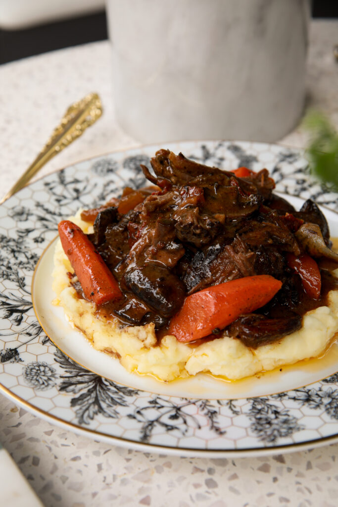 Close-up of tender slow cooker pot roast with carrots and glossy mushroom gravy.