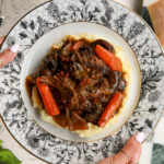 Slow cooked chuck roast surrounded by carrots and mushrooms in a rich savory gravy.