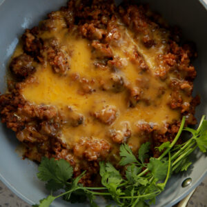 Cheesy taco rice cooked in a skillet with ground beef, melted cheddar, and fresh cilantro