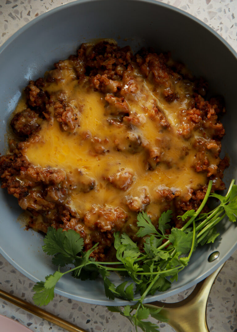 Cheesy taco rice cooked in a skillet with ground beef, melted cheddar, and fresh cilantro
