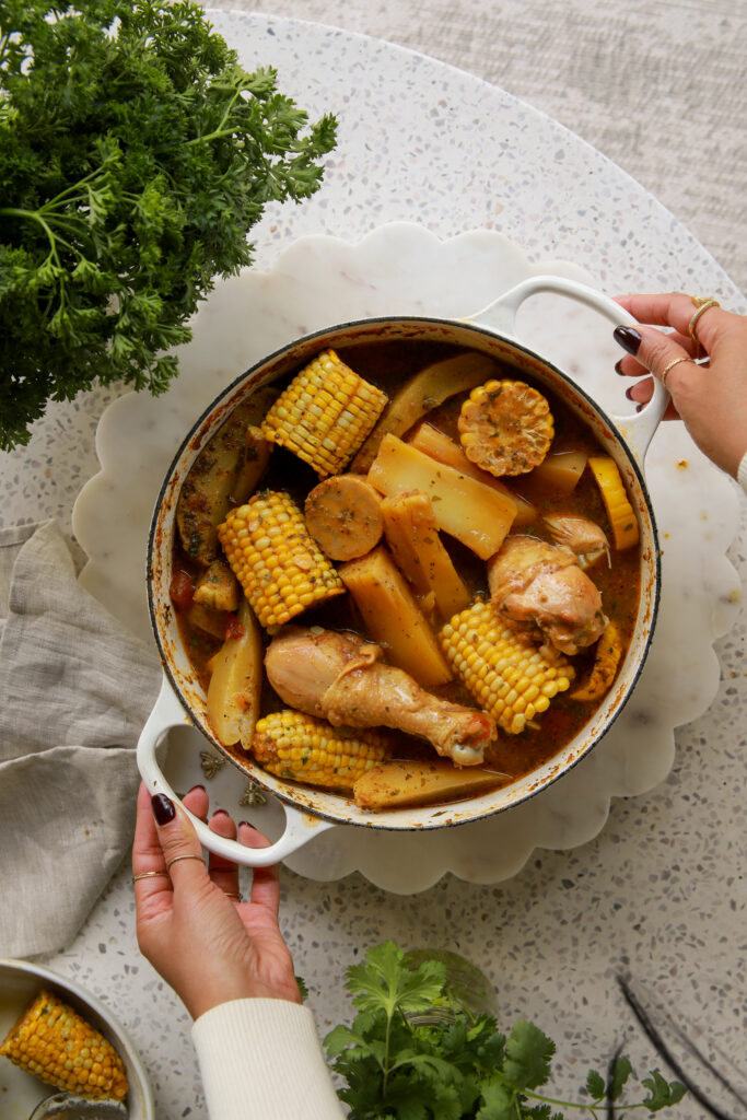 Panamanian caldo de pollo served in a bowl with bone-in chicken, yuca, corn, green plantain, and fresh cilantro
