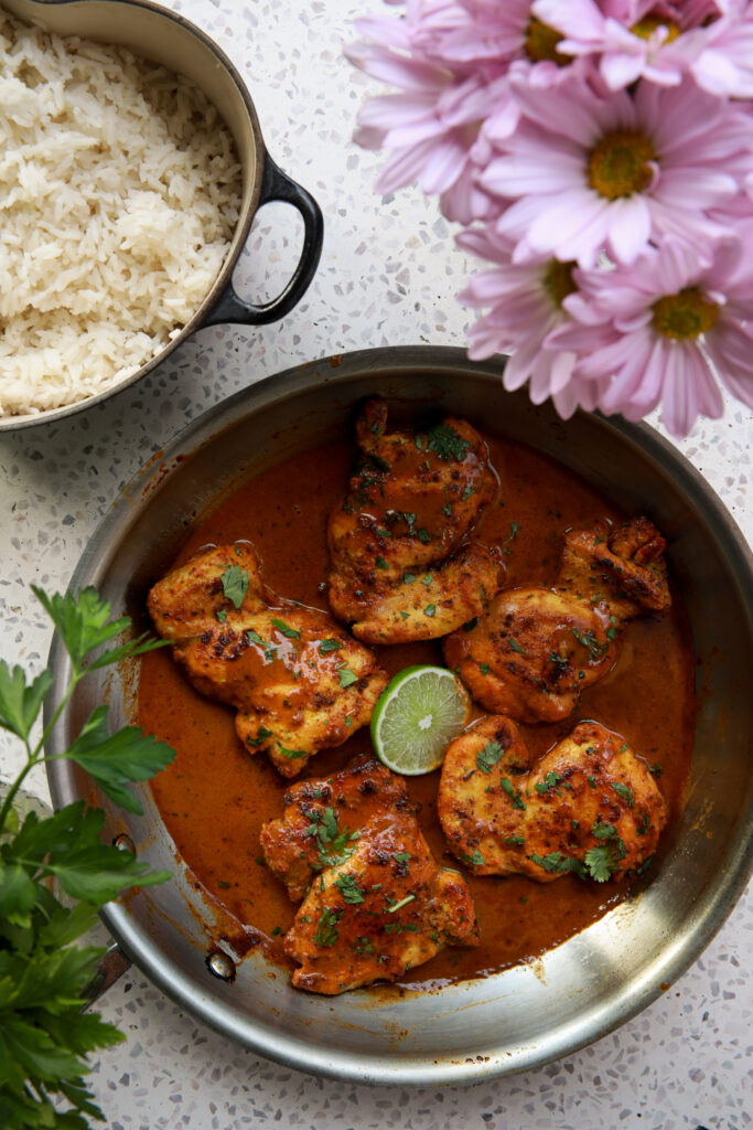 creamy coconut chicken simmering in a skillet with rich coconut sauce