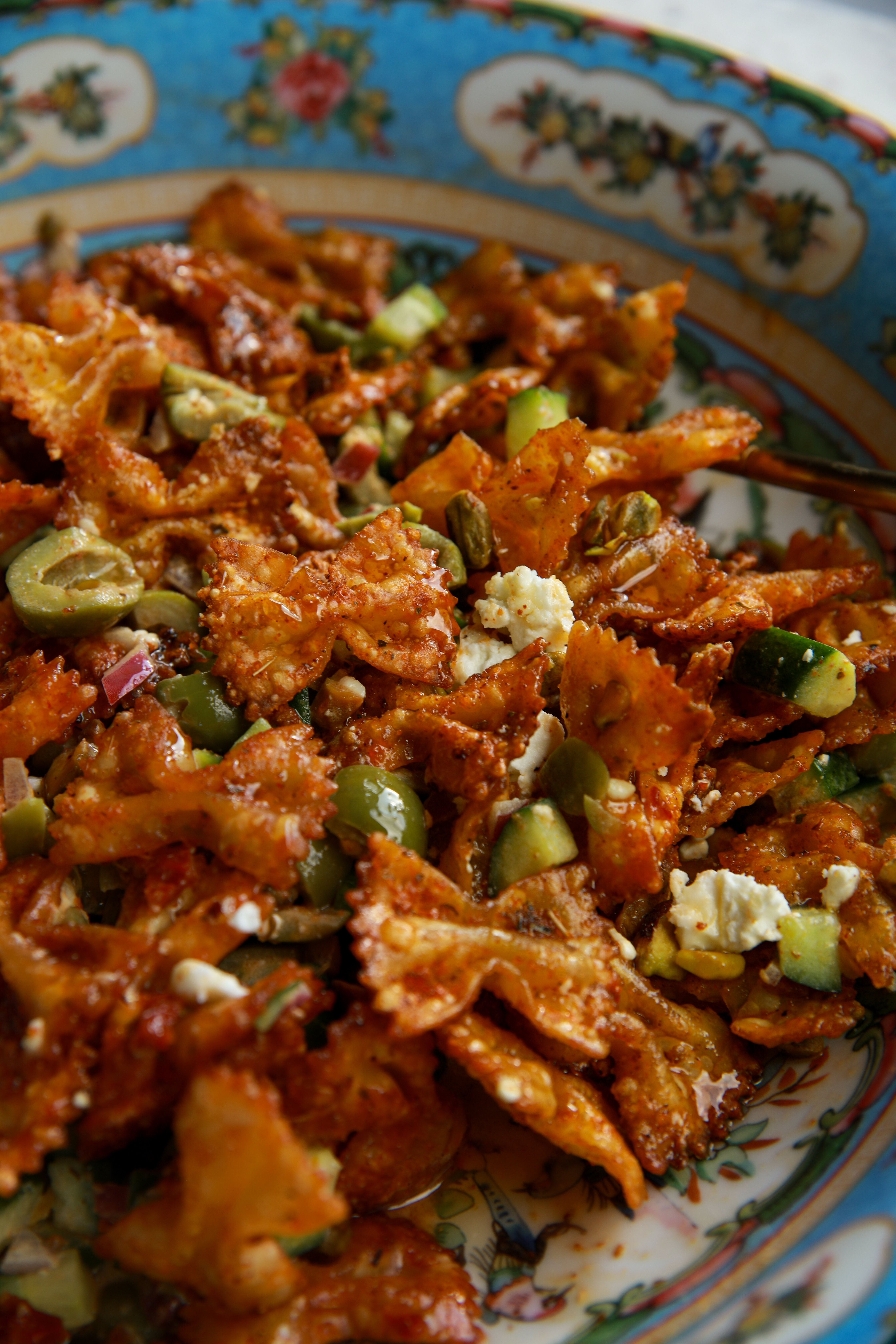Hot honey crispy pasta salad with feta, olives, pistachios, and sun-dried tomato dressing close up